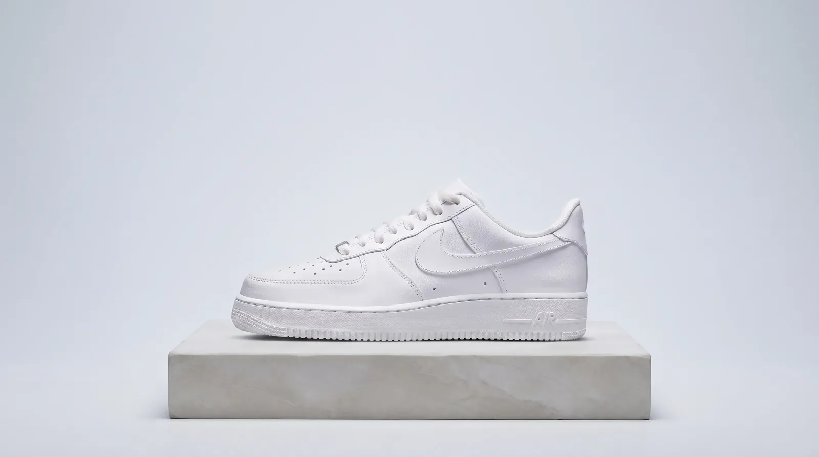 A complete white leather low-top shoe centered in a clean landscape product composition.